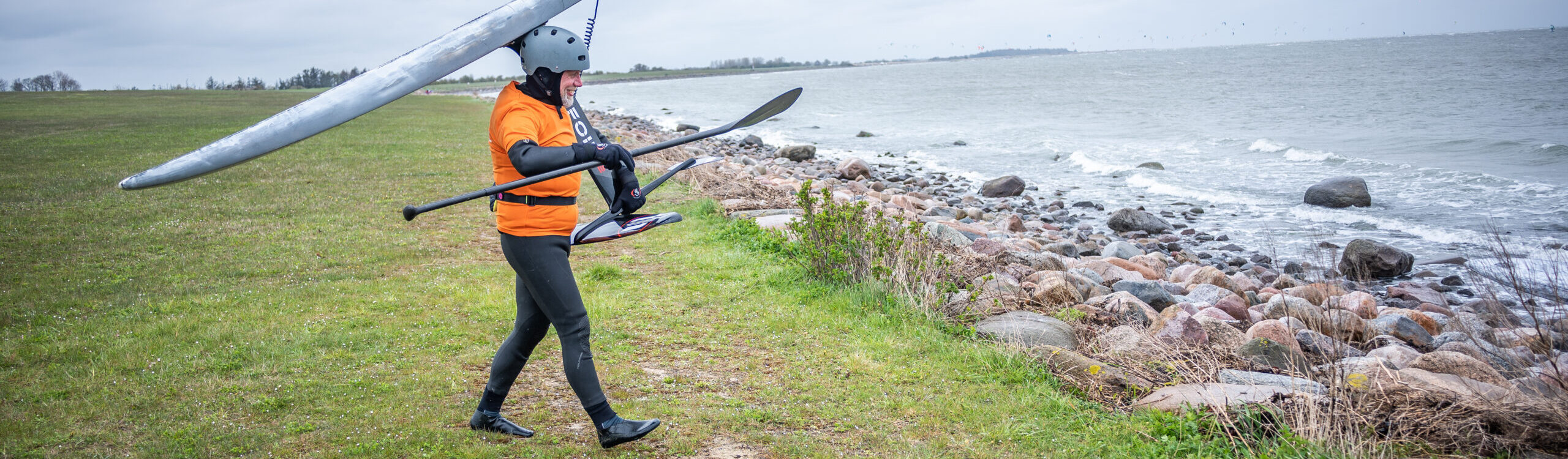 Frank auf dem Weg ins Wasser in Puttgarden SUP Downwindfoil Kurs
