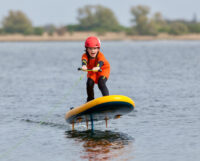 Kinder Foilen und Surfen über das Wasser auf Fehmarn