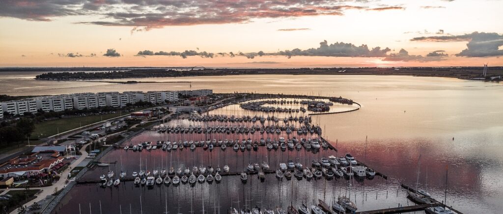 Drone_Jachthafen Yachthafen Burgtiefe bei Sonnenuntergang – Austragungsort des Foilfestivals auf Fehmarn mit Blick auf die Fehmarnsundbrücke