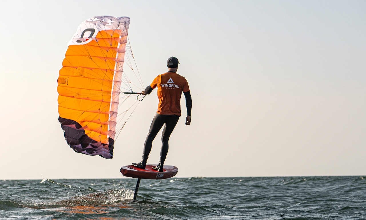 Trainer mit dem Parawing und Foilboard fliegt über die Ostsee