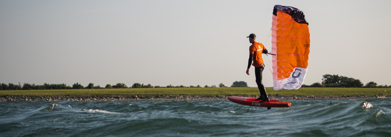 Breitbild_parawing Foiler mit dem Parawing schwebt über dem Meer auf Fehmarn