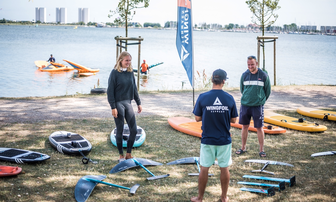 Wingfoil Lehrer auf der Wiese mit Schülern und Wingfoil Equipment